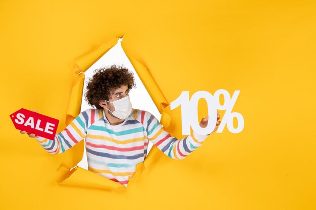 Vue de face jeune homme en tenue de masque et vente écrivant sur photo jaune santé covid couleur pandémie de coronavirus