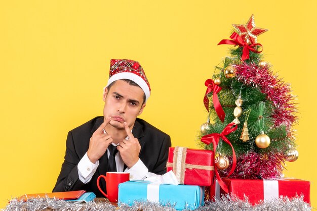 Vue de face jeune homme triste avec Bonnet de Noel mettant les doigts