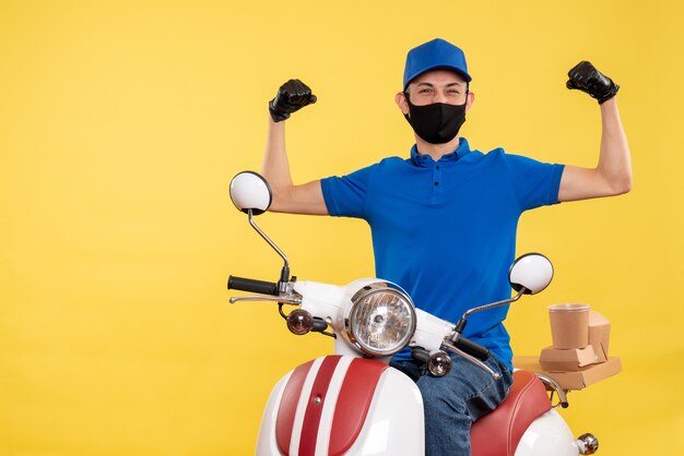 Vue de face jeune homme en uniforme bleu sur fond jaune covid- emploi service de livraison pandémique travail de vélo