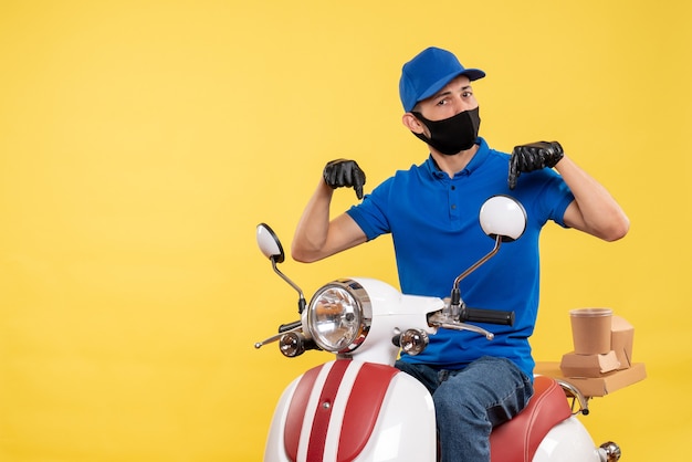 Vue de face jeune homme en uniforme bleu sur fond jaune covid- service pandémique travail vélo travail livraison