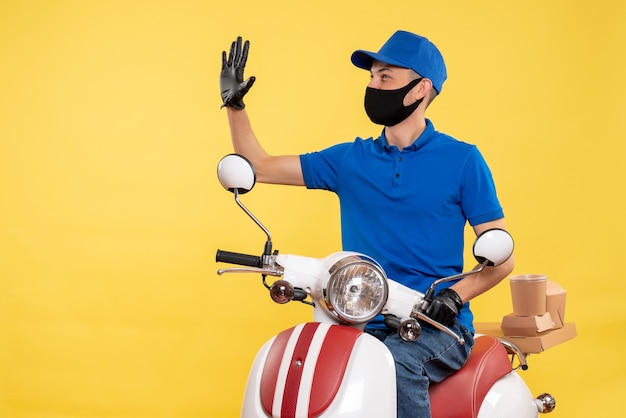 Vue de face jeune homme en uniforme bleu sur fond jaune covid- travail de travail de vélo de virus pandémique service service de pandémie