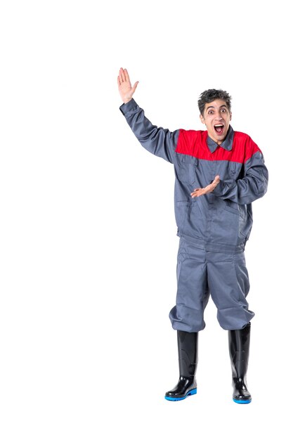 Vue de face jeune homme en uniforme avec une expression excitée sur une surface blanche