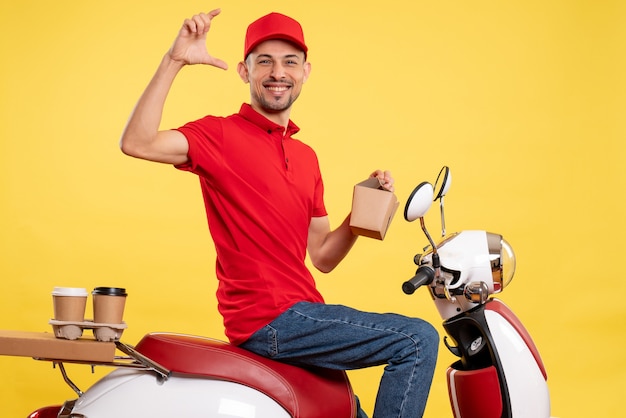 Vue de face jeune homme en uniforme rouge avec livraison de nourriture sur fond jaune