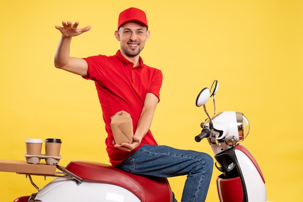 Vue de face jeune homme en uniforme rouge avec livraison de nourriture sur fond jaune