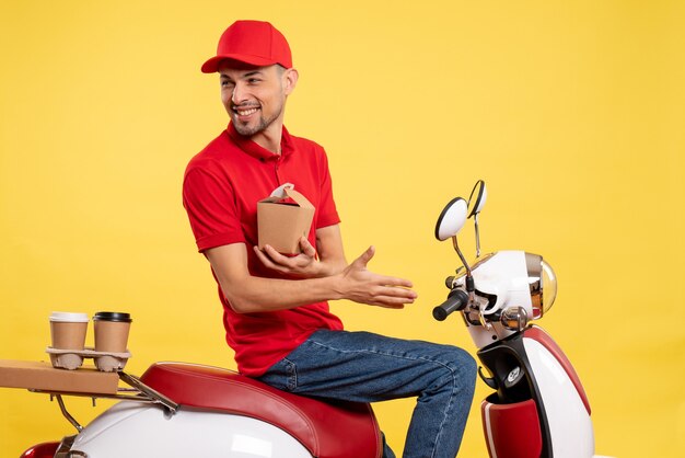 Vue de face jeune homme en uniforme rouge avec peu de nourriture de livraison sur fond jaune