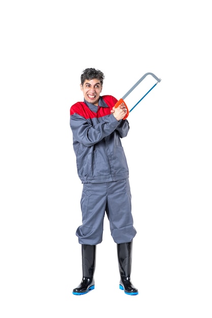 Vue de face jeune homme en uniforme avec scie à métaux sur une surface blanche