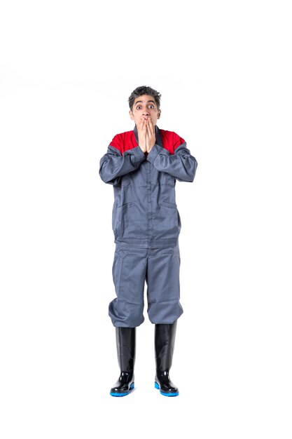 Vue de face jeune homme en uniforme spécial avec une expression choquée sur une surface blanche