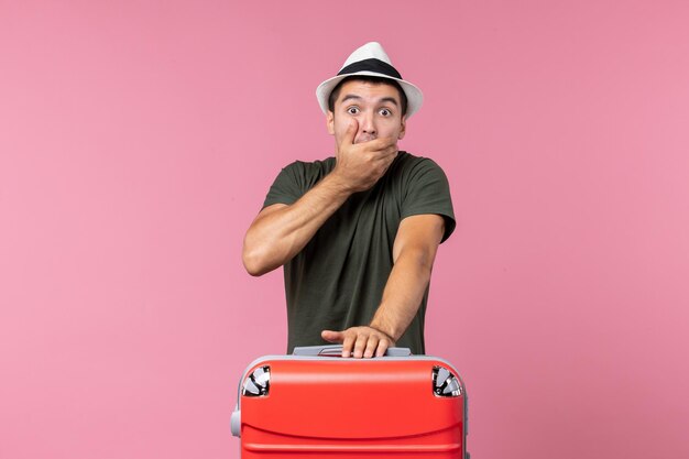 Vue de face jeune homme en vacances avec un gros sac choqué sur un espace rose