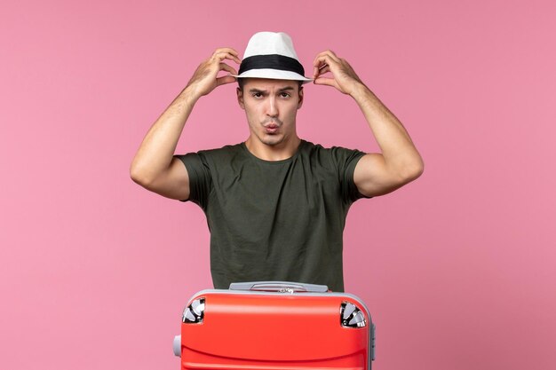 Vue de face jeune homme en vacances portant un chapeau sur l'espace rose