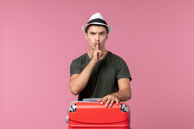 Vue de face jeune homme en vacances avec sac rouge sur l'espace rose