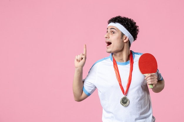 Vue de face jeune homme en vêtements de sport avec médaille sur mur rose