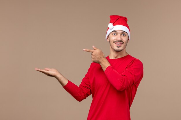 Vue de face jeune homme avec visage excité sur plancher brun vacances d'émotion de Noël