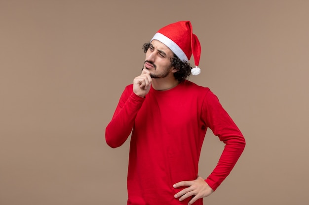 Vue de face jeune homme avec visage pensant sur fond marron vacances d'émotion de Noël