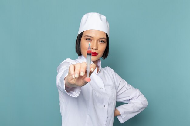 Une vue de face jeune infirmière en costume médical blanc tenant l'injection sur le médecin de l'hôpital médecine bureau bleu