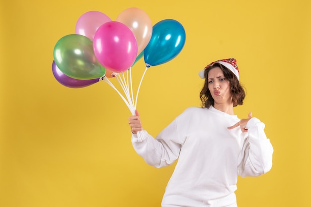 Vue de face jeune jolie femme tenant des ballons sur jaune Noël nouvel an couleur femme émotion