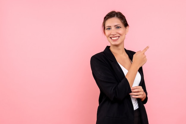 Vue de face jeune jolie femme en veste sombre sur fond rose