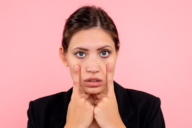 Vue de face jeune jolie femme avec visage fatigué sur fond rose