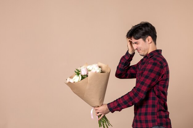 Vue de face jeune mâle donnant de belles fleurs sur un mur marron