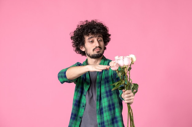 Vue de face jeune mâle avec des roses roses sur la couleur rose