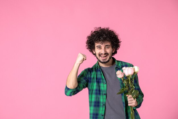 Vue de face jeune mâle avec des roses roses sur rose