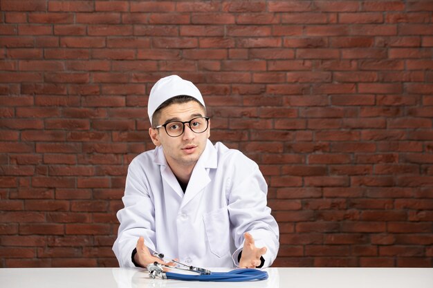 Vue de face jeune médecin en costume médical blanc