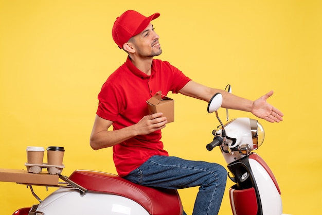 Vue de face jeune messager en uniforme rouge avec peu de salutation de nourriture de livraison sur fond jaune