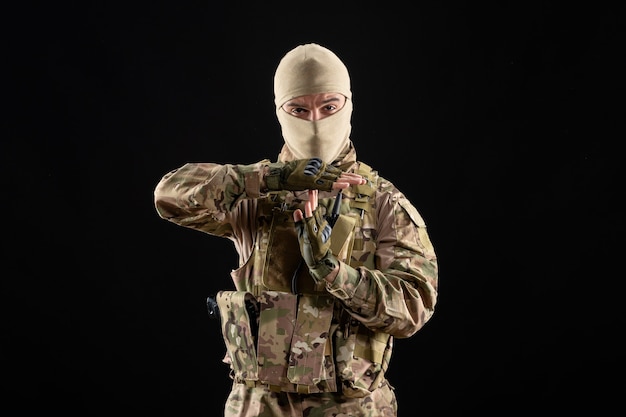 Photo gratuite vue de face jeune soldat en uniforme sur le mur noir