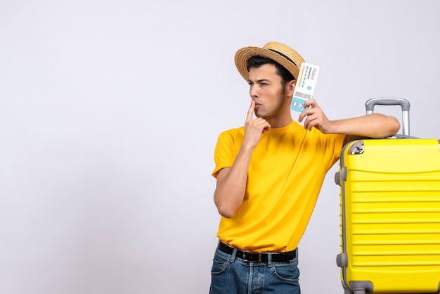 Vue de face jeune touriste debout près de valise jaune déroutant