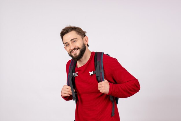 Vue de face jeune touriste mâle avec sac à dos souriant sur mur blanc avion covid vacances émotion virus vol couleur