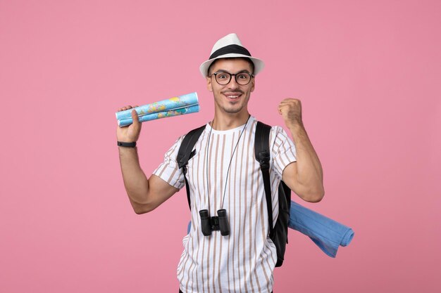 Vue de face jeune touriste masculin avec des cartes sur fond rose