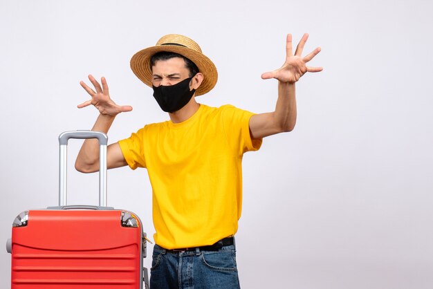 Vue de face jeune touriste avec t-shirt jaune et valise rouge