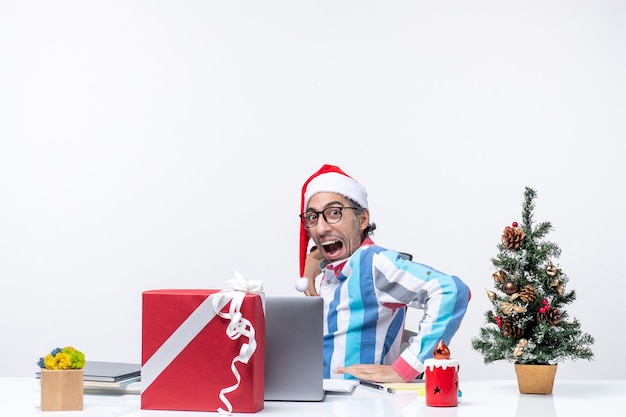 Vue de face jeune travailleur masculin assis dans son lieu de travail sur un bureau blanc