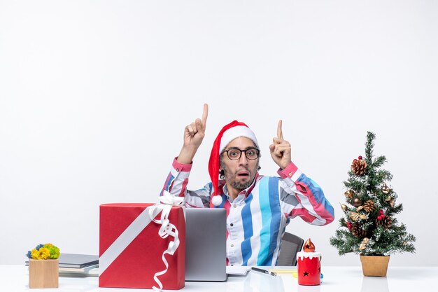 Vue de face jeune travailleur masculin assis dans son lieu de travail confus sur fond blanc