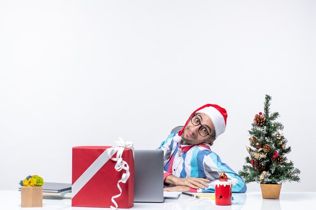 Vue de face jeune travailleur masculin assis dans son lieu de travail sur fond blanc