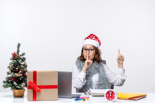 Vue de face jeune travailleuse assise devant son lieu de travail sur fond blanc