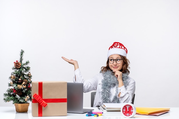 Vue de face jeune travailleuse assise devant son lieu de travail pensant sur fond blanc