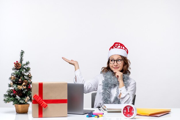 Vue de face jeune travailleuse assise devant son lieu de travail pensant sur fond blanc