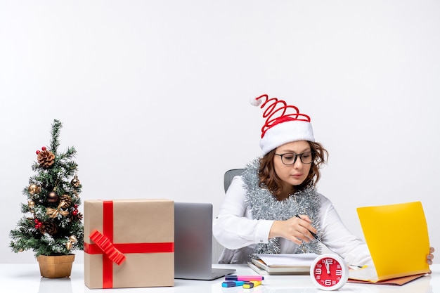 Vue de face jeune travailleuse au lieu de travail, écrire des notes sur fond blanc