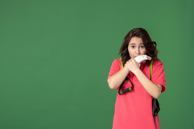 Vue de face jeune vendeuse avec un bandage sur sa main blessée sur une surface verte