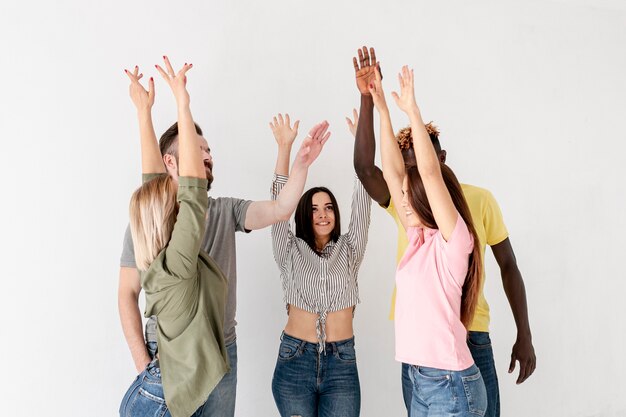 Vue de face de jeunes amis avec les mains levées