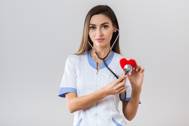 Vue de face joli médecin tenant un coeur en peluche