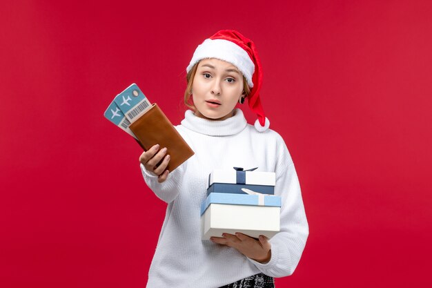 Vue de face jolie dame avec des billets et des cadeaux sur un bureau rouge