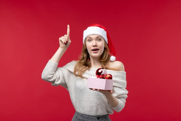 Vue de face de jolie femelle avec des jouets de Noël sur le rouge