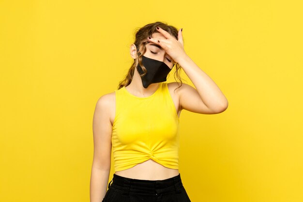 Vue de face de jolie femme ayant des maux de tête sur jaune