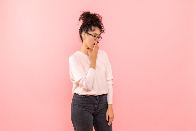 Vue de face de la jolie femme bâillant sur le mur rose