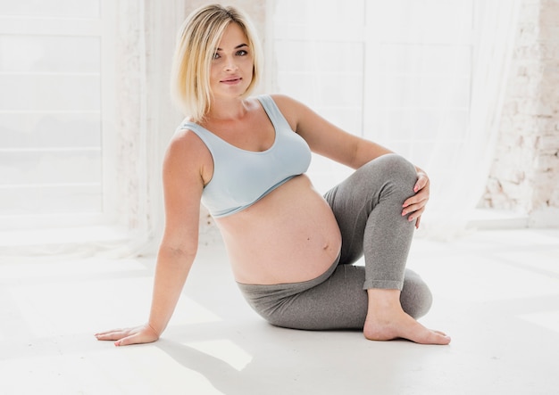 Vue de face jolie femme enceinte faisant du yoga