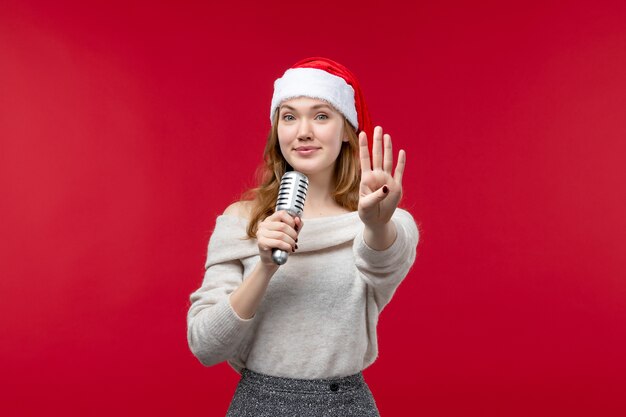 Vue de face d'une jolie femme avec un micro montrant le numéro en rouge