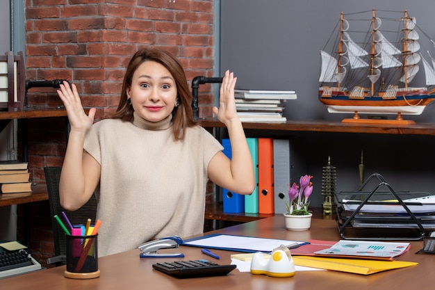 Vue de face d'une jolie femme montrant sa surprise en travaillant au bureau