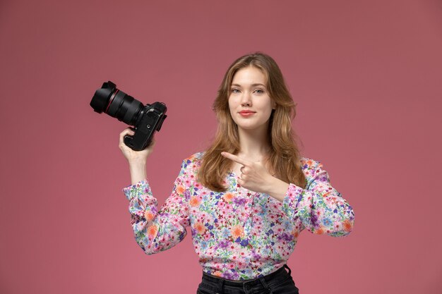 Vue de face jolie femme montre sa photocamera avec son index