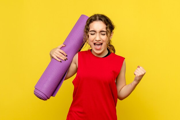 Vue de face de la jolie femme se réjouissant avec tapis violet sur jaune